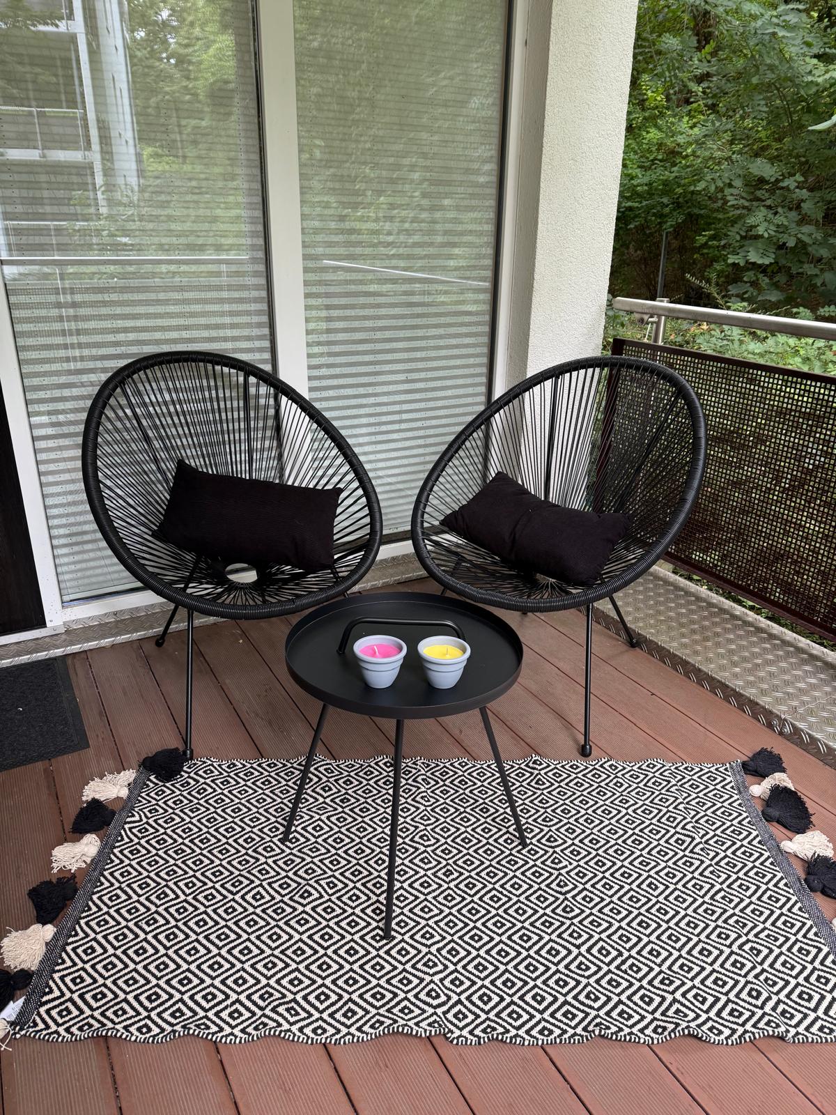 Überdachter Balkon mit zwei Sesseln, kleinem Tisch und Outdoor-Teppich – Außenbereich an der frischen Luft